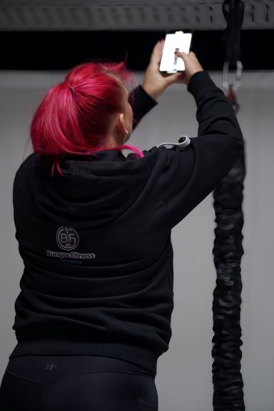 Person mit pinken Haaren macht ein Foto mit einem Smartphone.